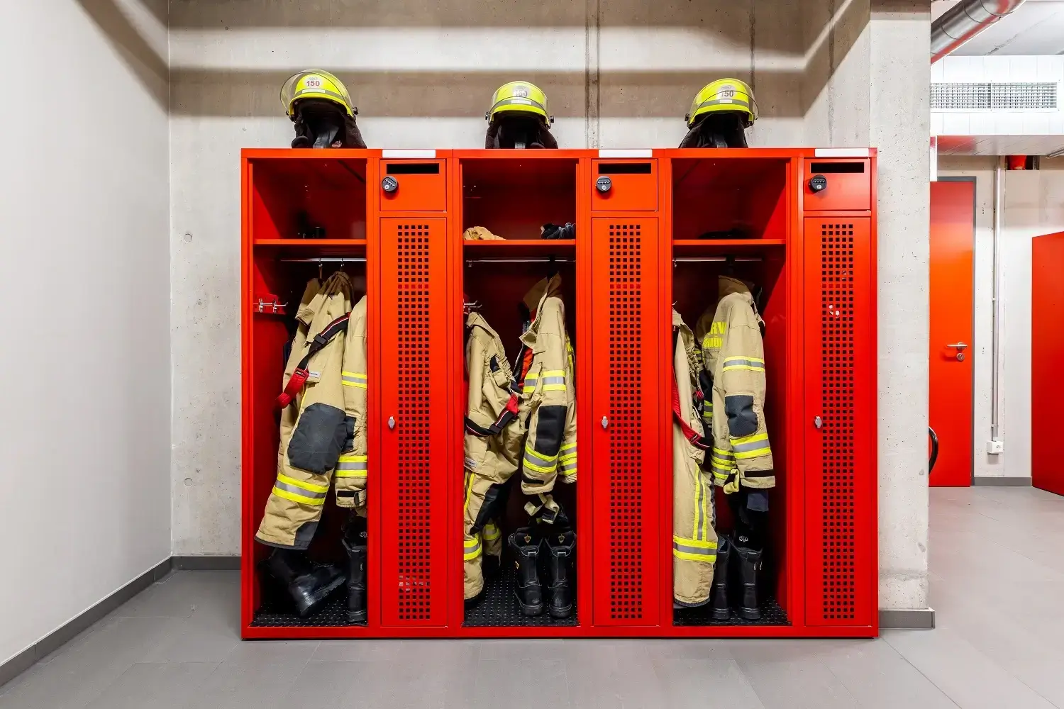 Red Eurobox fire-brigade lockers holding turnout gear and helmets