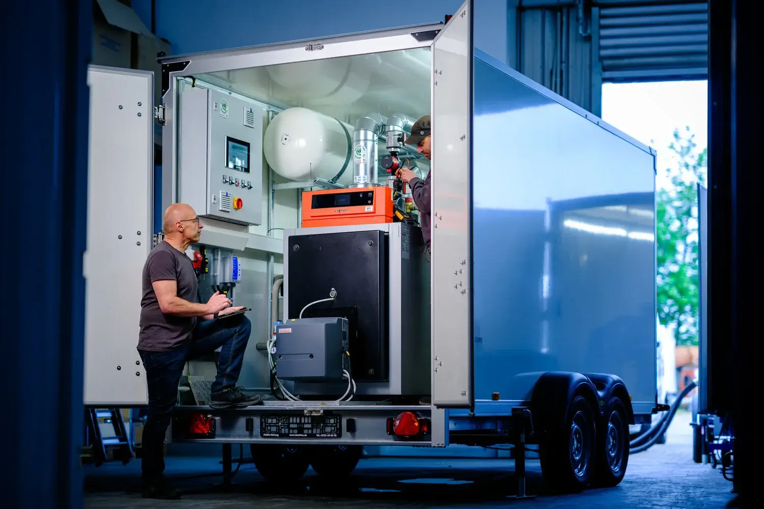Open HeizMax heating trailer with two technicians working on the heating unit